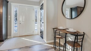 A hallway with a white door, a round mirror, and a small dining table with chairs. - Up North Living!  Fully renovated one-level living home in wooded lot near lake. (Cumberland)
