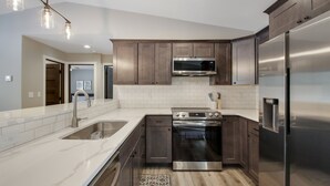 A modern kitchen with stainless steel appliances, dark wooden cabinets, and a white tile backsplash. - Up North Living!  Fully renovated one-level living home in wooded lot near lake. (Cumberland)