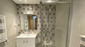 A modern bathroom with a glass shower enclosure, a white sink, and a tiled backsplash.