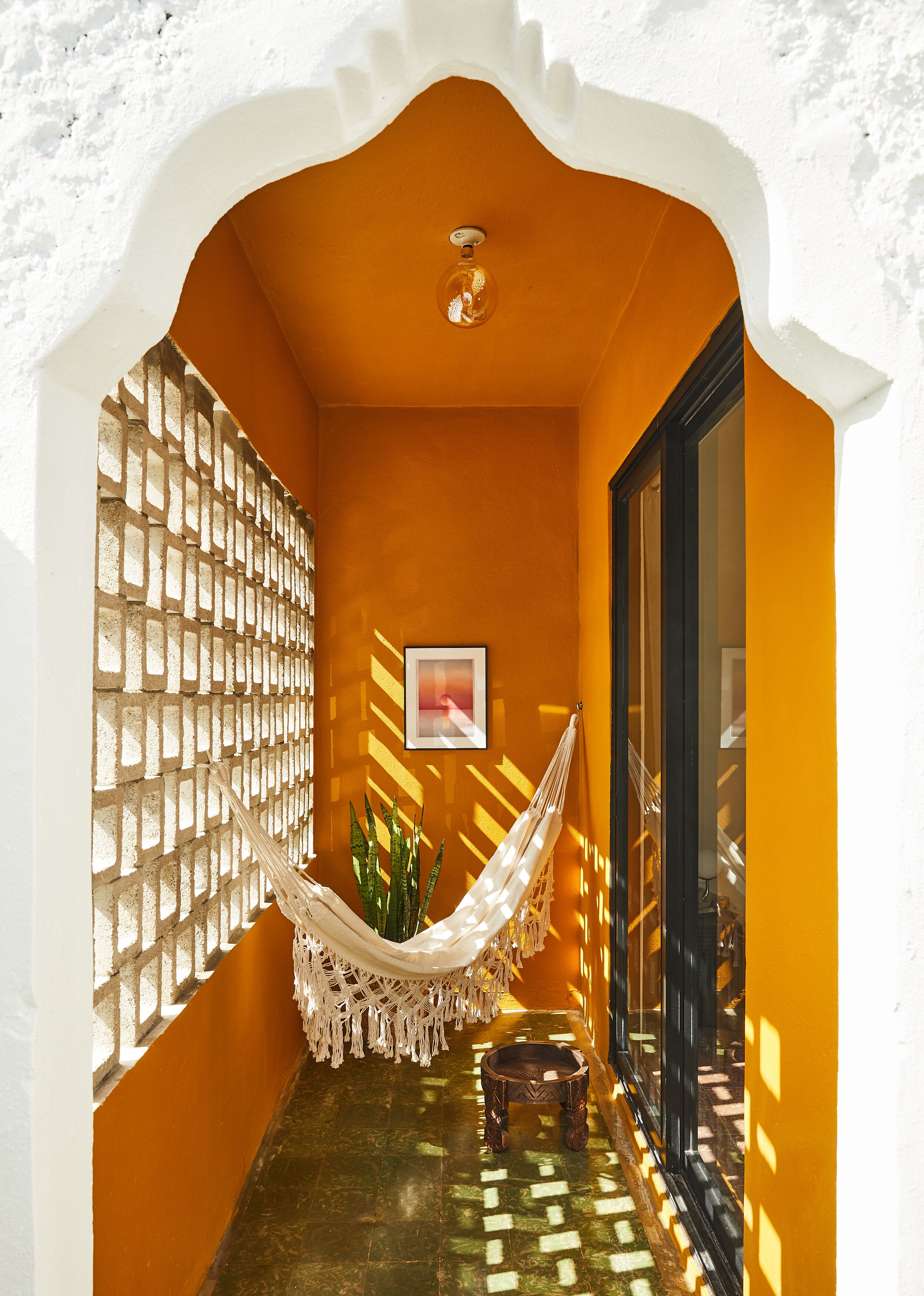 A narrow hallway with a hammock, a small table, and a framed picture on the wall.