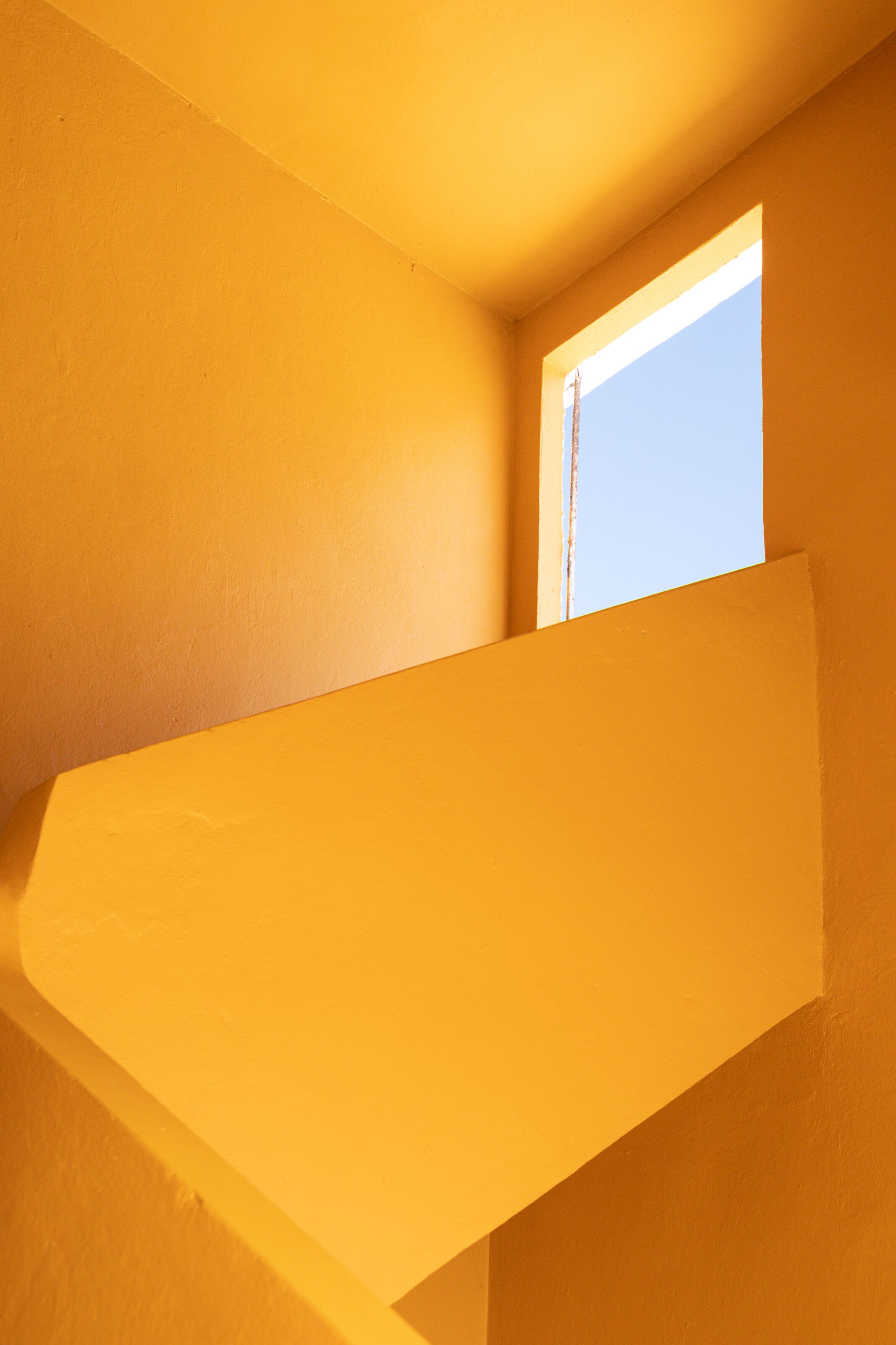 A corner of a room with a window and a sloped ceiling.