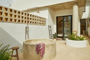 A modern outdoor area with a concrete water feature, a wooden stool, and a planter with plants. - APT by DW (San Juan)