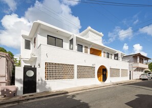 A modern two-story building with numbered doors, a visible entrance, and a clear sky. - APT by DW (San Juan)