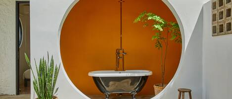 Una bañera en un rincón circular con una pared blanca y un fondo naranja.