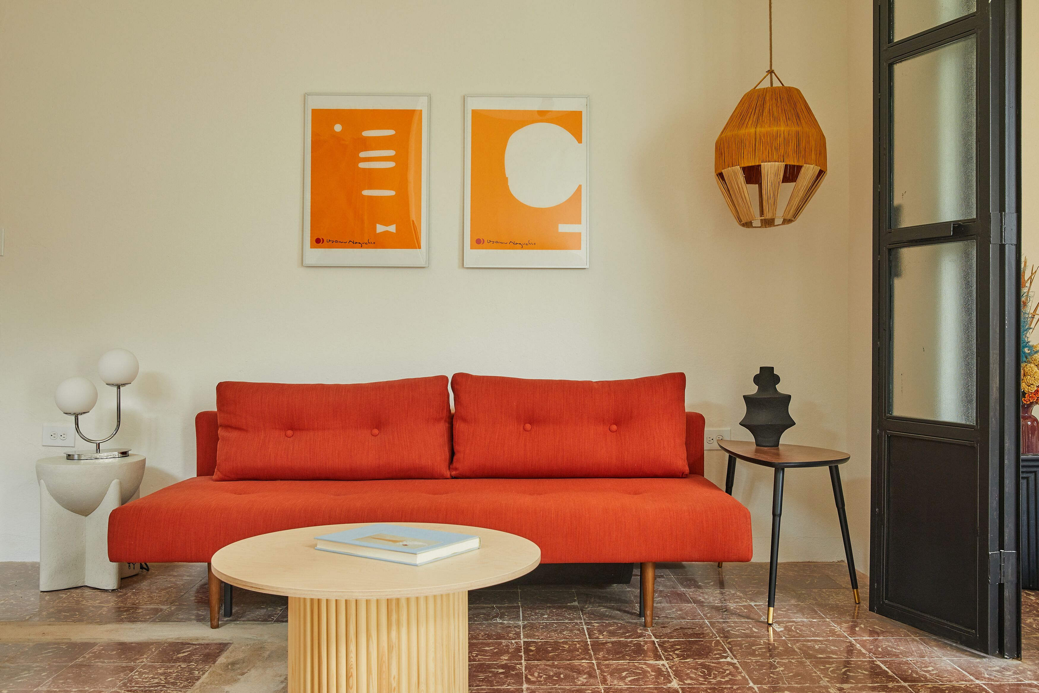 Una sala de estar moderna con un sofá rojo, una mesa de centro redonda y dos cuadros enmarcados en la pared.