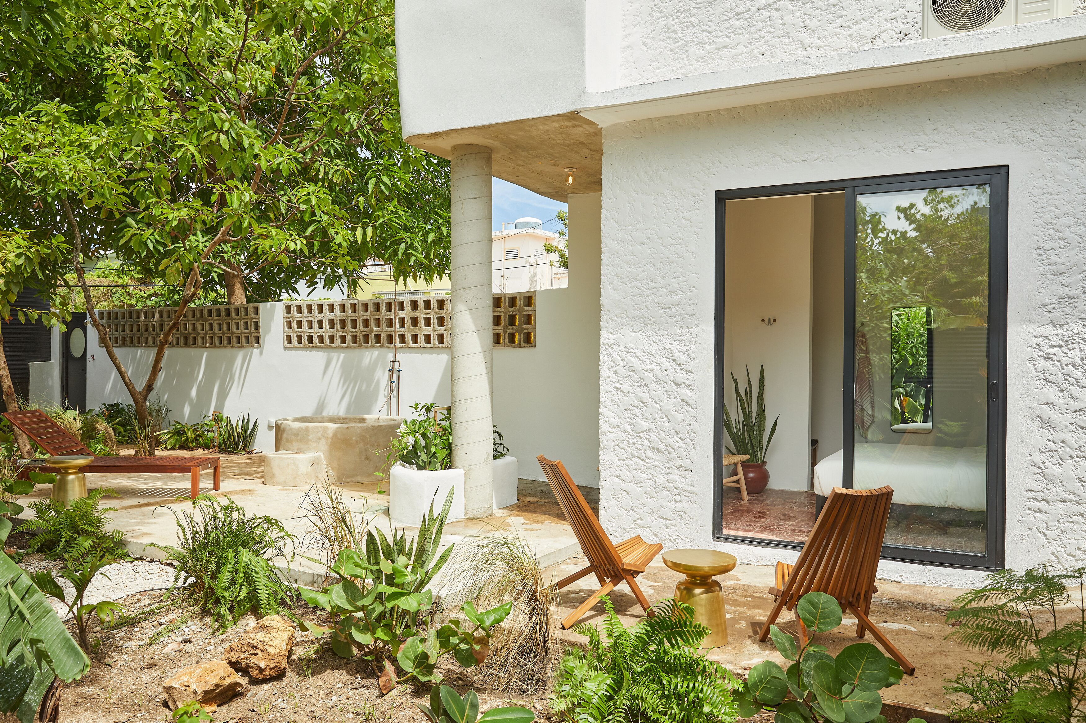 A modern outdoor patio with a seating area, a large window, and various plants.