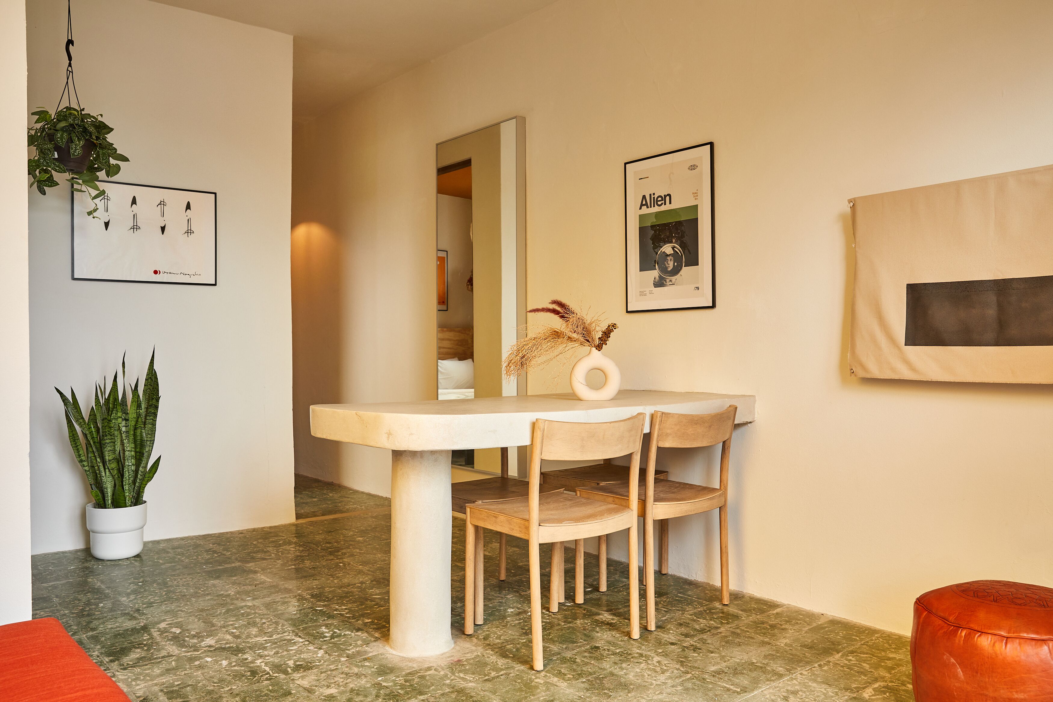 Een eetgedeelte met een tafel, stoelen, een potplant en kunstwerken in lijsten aan de wanden.