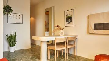 Een eetgedeelte met een tafel, stoelen, een potplant en kunstwerken in lijsten aan de wanden.