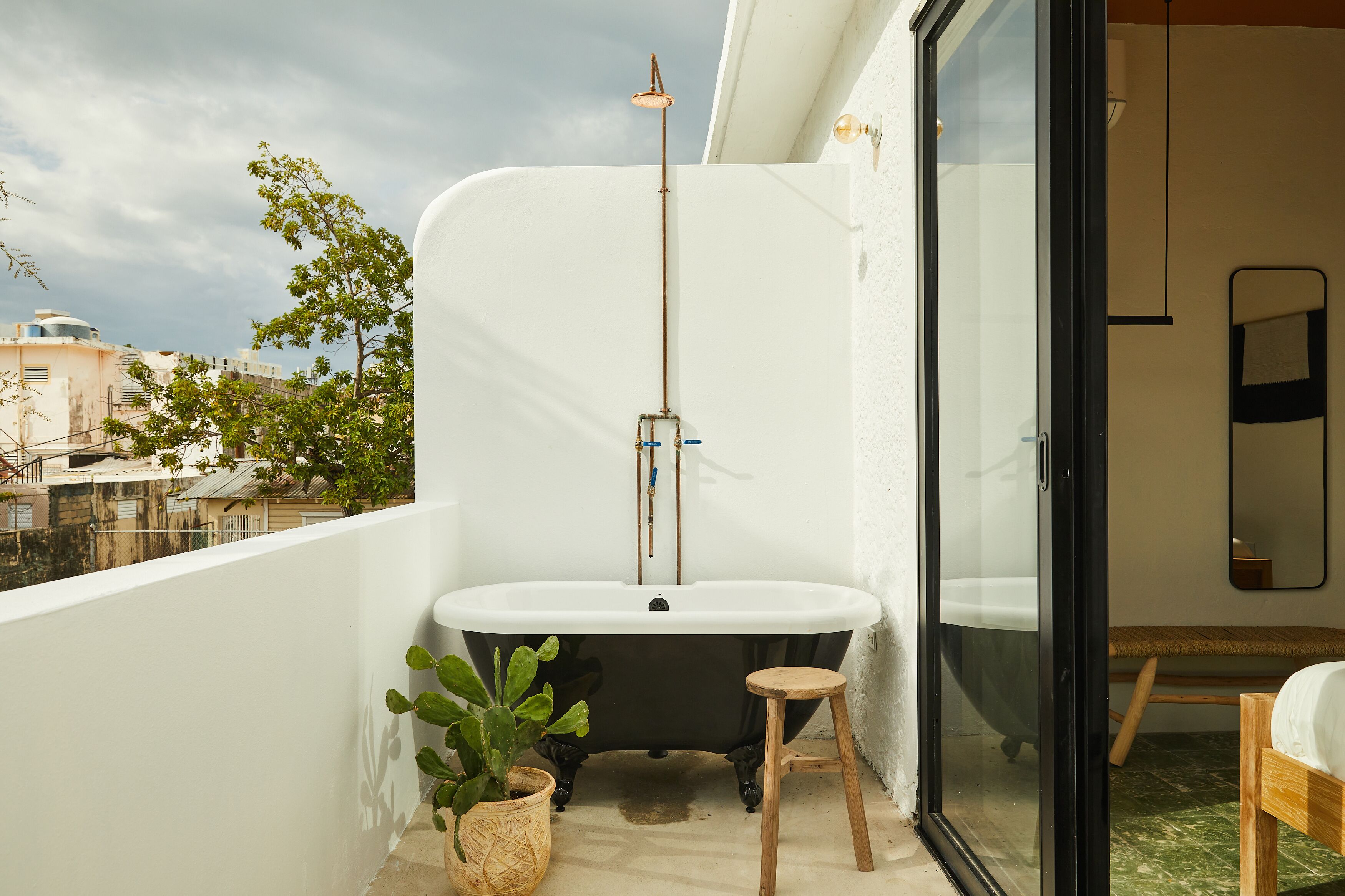 A modern bathroom with a freestanding bathtub, a small stool, and a potted plant.