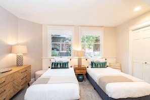 Une chambre avec deux lits, une commode en bois et deux tables de chevet avec des lampes.