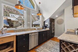 A kitchen with dark cabinets, a stainless steel dishwasher, a granite countertop, and pendant lighting. - Peaceful Home-like Condo Spacious, Private Deck, Fireplace 3 Bedroom Condo by RedAwning (Telluride)