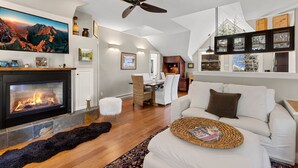 Ein modernes Wohnzimmer mit Kamin, Deckenventilator und Essbereich.