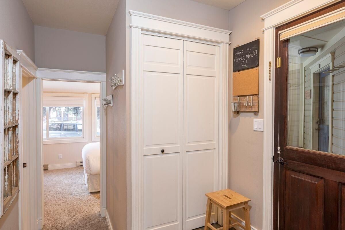 A hallway with a white wardrobe, a small stool, and a chalkboard with a message.