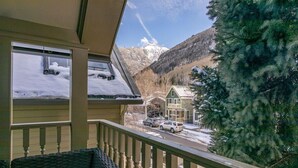Ein Balkon mit Blick auf einen schneebedeckten Berg und ein Gebäude mit grüner Dachbegrünung.