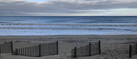 A beach with a wooden fence and sandy terrain.
