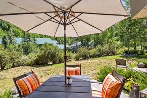 An outdoor patio with a table, chairs, and a large umbrella.