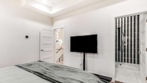 Moderni makuuhuone, jossa on sänky, televisio ja suihkutila.