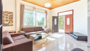 Amplia sala de estar con techo de madera, un ventanal grande, un sofá, una mesa de centro y una puerta.