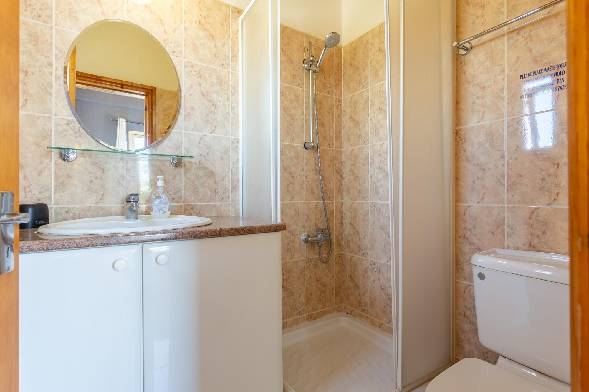 A bathroom with a sink, mirror, toilet, and shower.