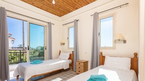 Una habitación con dos camas, techo de madera y ventanas amplias con cortinas.
