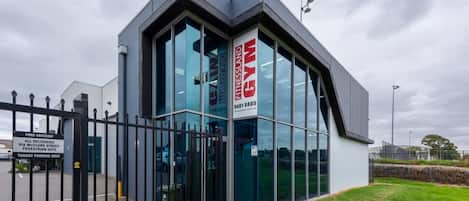 A modern building with large glass windows and a sign indicating it is a gym.