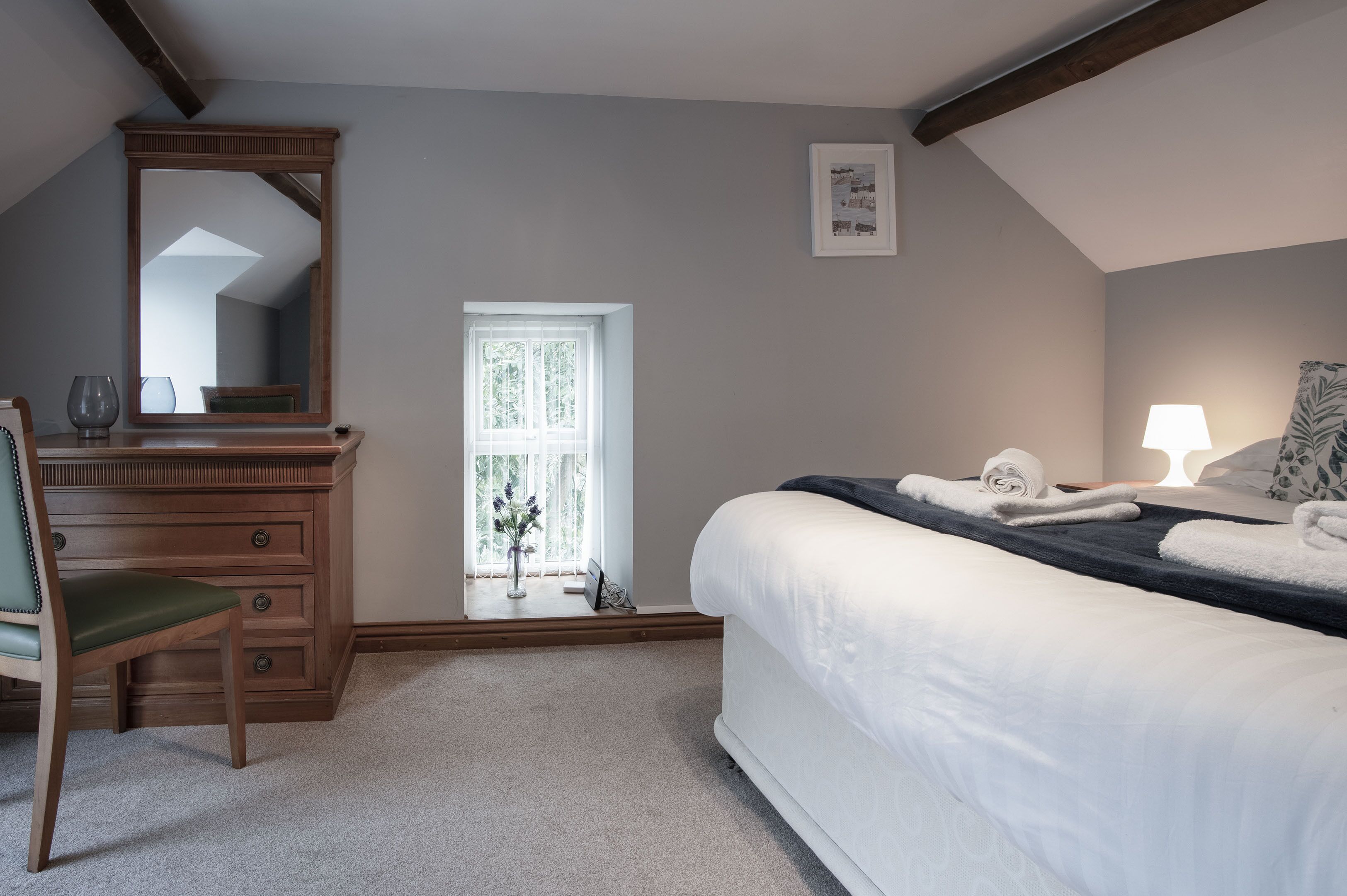 A bedroom with a bed, a dresser, a chair, a window, and a framed picture on the wall.