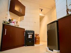A compact kitchen with a black stove, a refrigerator, and wooden cabinets.