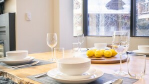 Une table à manger dressée avec des bols blancs, des verres et des citrons, et une fenêtre donnant sur un paysage enneigé.