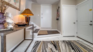 A hallway with a white door, a staircase with a beige mat, a lamp, and a decorative vase. - Immaculate 2-bed in Dallas Close to Everything! (Dallas)