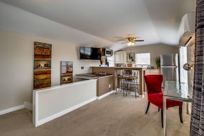 Cocina compacta con comedor, que incluye televisión, microondas y ventilador de techo.