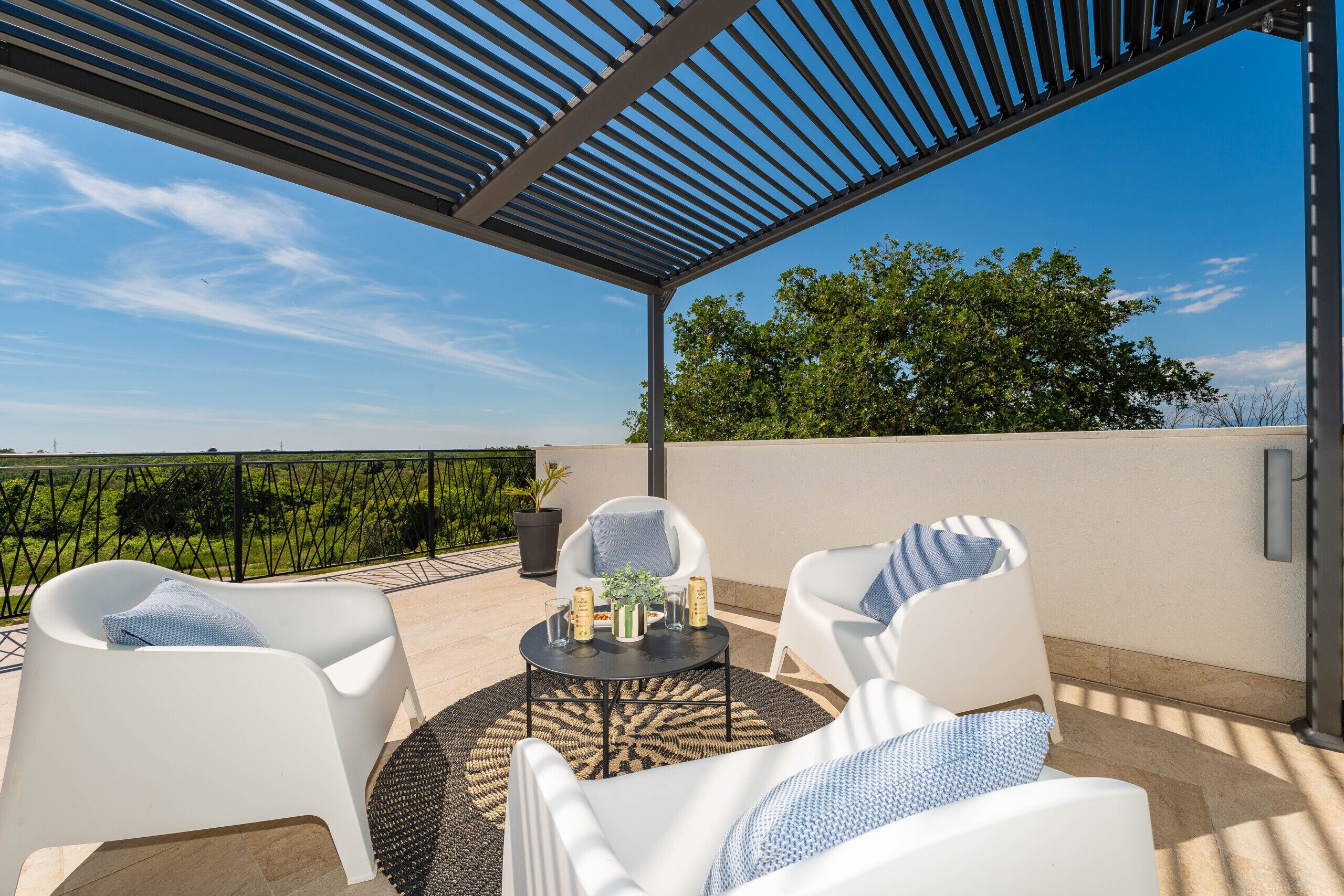 An outdoor patio with white chairs, a round table, and a pergola.