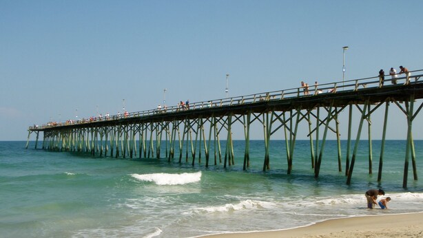 A pier extending into the ocean with people walking along it.