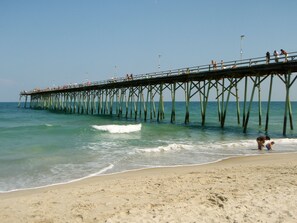 A pier extending into the ocean with people walking along it. - Salty Knights Centrally Located to Beach and Boardwalk (Carolina Beach)
