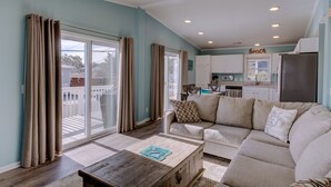 A spacious living room with a large sofa, a coffee table, and a ceiling fan.
