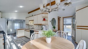 Une cuisine moderne avec des meubles blancs, un îlot central et un coin repas comprenant une table ronde et des chaises.
