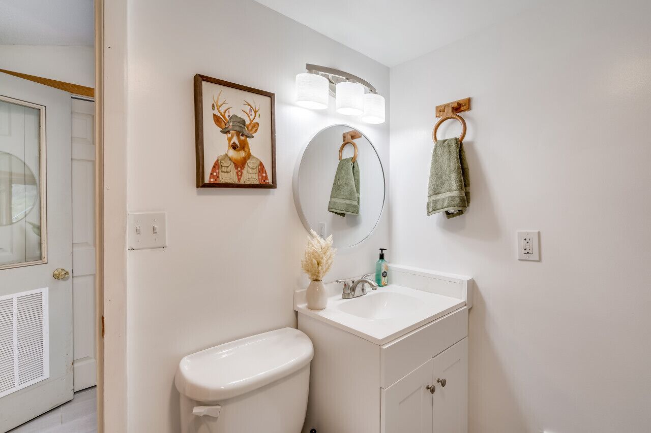 Ein Badezimmer mit Toilette, Waschbecken, Spiegel und Handtuchhalter.