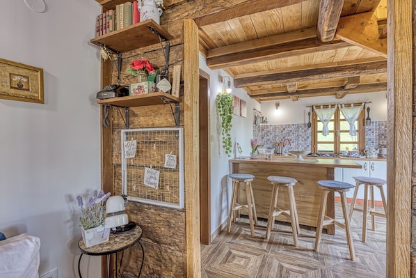 A rustic kitchen with wooden beams, a herringbone-patterned floor, and a bar area with stools. - Rural House With Wellness (Sveti Ivan Zelina)