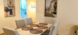 A dining area with a table set for four, surrounded by grey upholstered chairs.