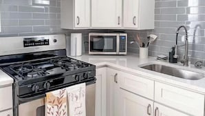 Una cucina moderna con mobili bianchi, un piano cottura nero, un forno a microonde e un lavello.