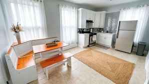 Una cucina compatta con mobili bianchi, un forno a microonde, un fornello e un frigorifero.