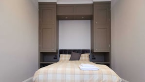 A bedroom with a bed, a headboard, and built-in storage cabinets.