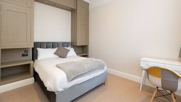 A bedroom with a bed, a desk, and built-in shelving.