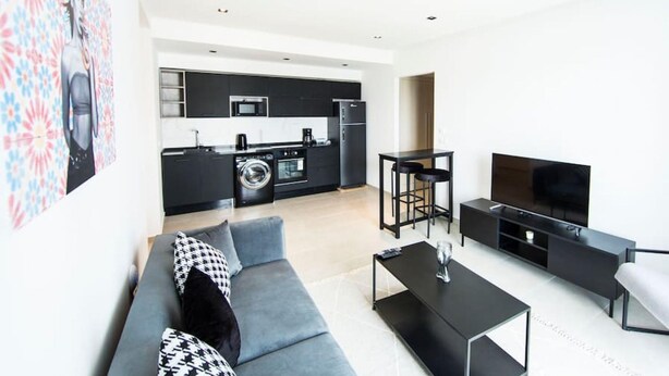 A modern apartment with a living room, kitchen, and dining area. - Sunset 302 Apt de Luxe Avec Salle de Fitness (Tunis)