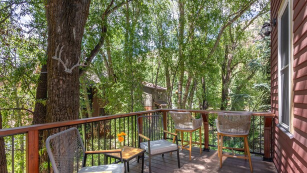 A wooden deck with chairs and a table, surrounded by trees. - Snowy Peak Views From Living Room, 2 Parking Spaces, Walk To Ski 1 Bedroom Condo by RedAwning (Telluride)