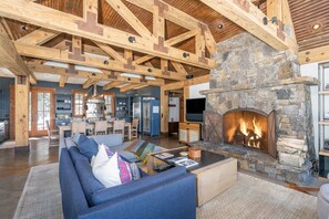 Ein geräumiges Wohnzimmer mit Kamin aus Stein, Holzbalken und einem großen Sofa.
