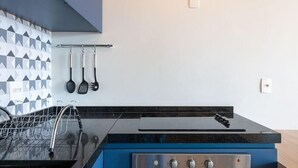A kitchen with a black countertop, stainless steel appliances, and a backsplash with geometric tiles. - Huma Klabin (São Paulo)