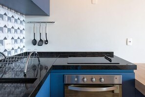 Una cocina con encimera negra, electrodomésticos de acero inoxidable y salpicadero con azulejos geométricos.