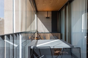 Un espacio moderno al aire libre con mesa y sillas, ventanas amplias y techo de madera.