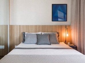A hotel room with a bed, a nightstand, a lamp, a framed picture on the wall, and a window with curtains. - Huma Klabin (São Paulo)