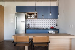 Una cocina moderna con encimera azul, electrodomésticos de acero inoxidable y lámparas colgantes.